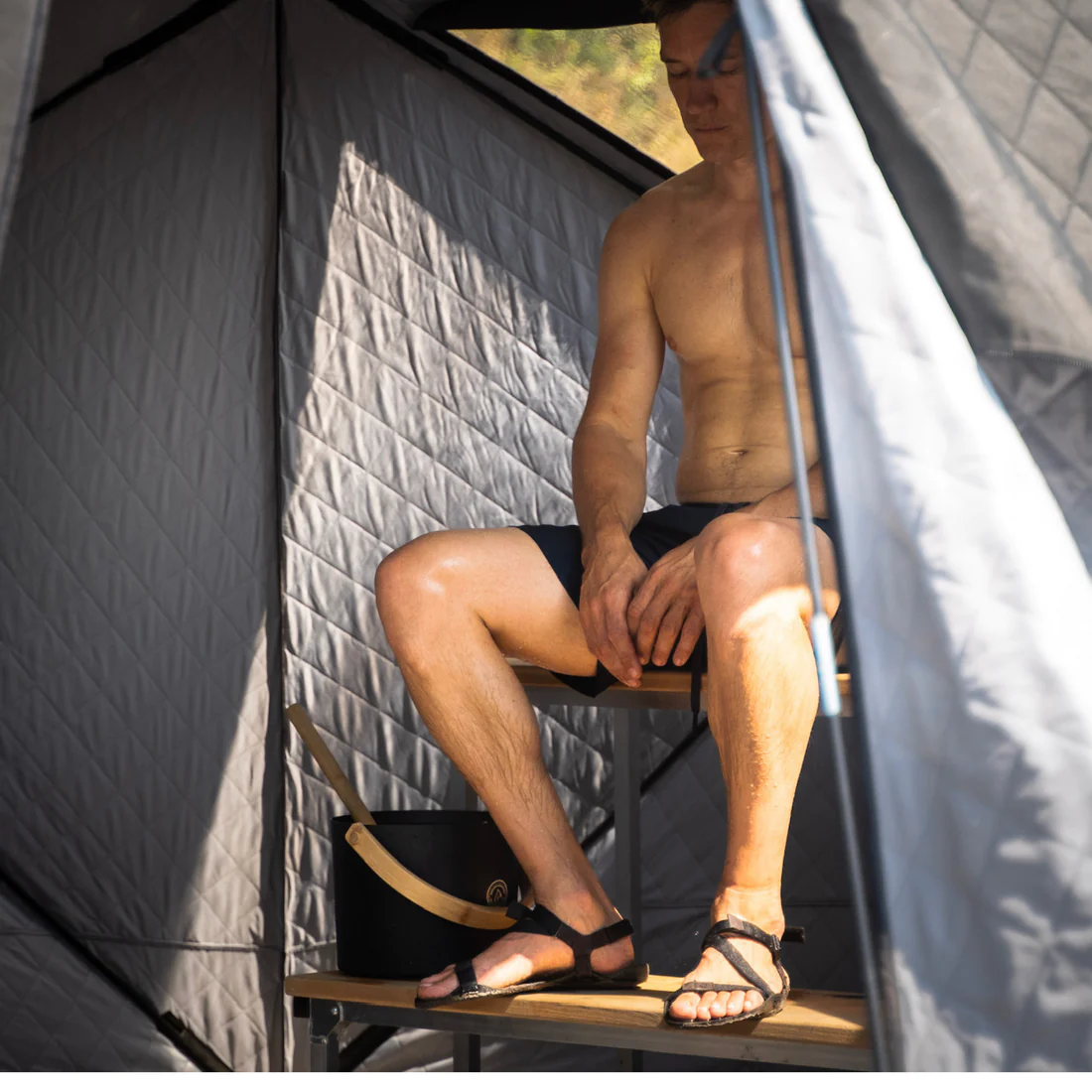 Sitting on the upper bench of a north shore sauna tent with portable bench